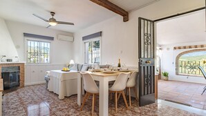 A dining area with a table set for four, a fireplace, and a view through a glass door. - Awesome home in Guaro (Guaro)