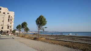 A coastal area with a building, trees, and a beach. - Enles Hotel (Durrës)
