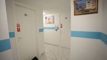 Un pasillo con puertas numeradas 1 y 4, un cuadro en la pared y una franja azul en las paredes.