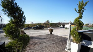 A parking area with a wooden deck, a white column, and a potted plant. - Enles Hotel (Durrës)