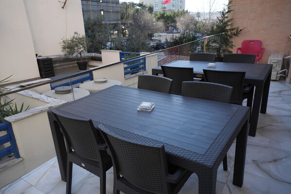 An outdoor patio area with a table and chairs, a small potted plant, and a red chair. - Enles Hotel (Durrës)