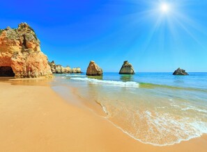A beach with clear blue water, a sandy shore, and rock formations. - Prainha Calm Retreat in Alvor (Portimão)