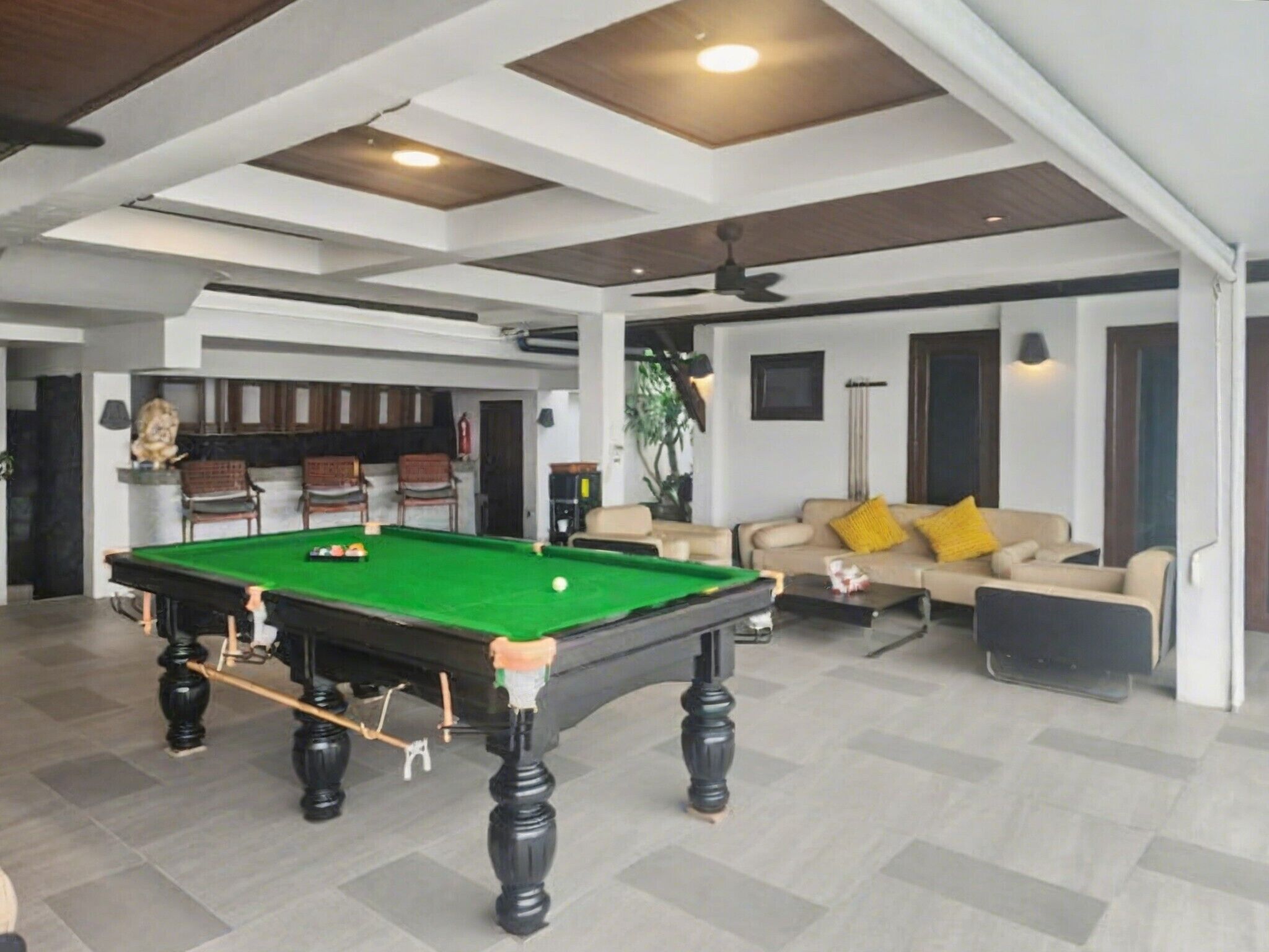 A spacious indoor area with a pool table, a sofa set, and a bar area.