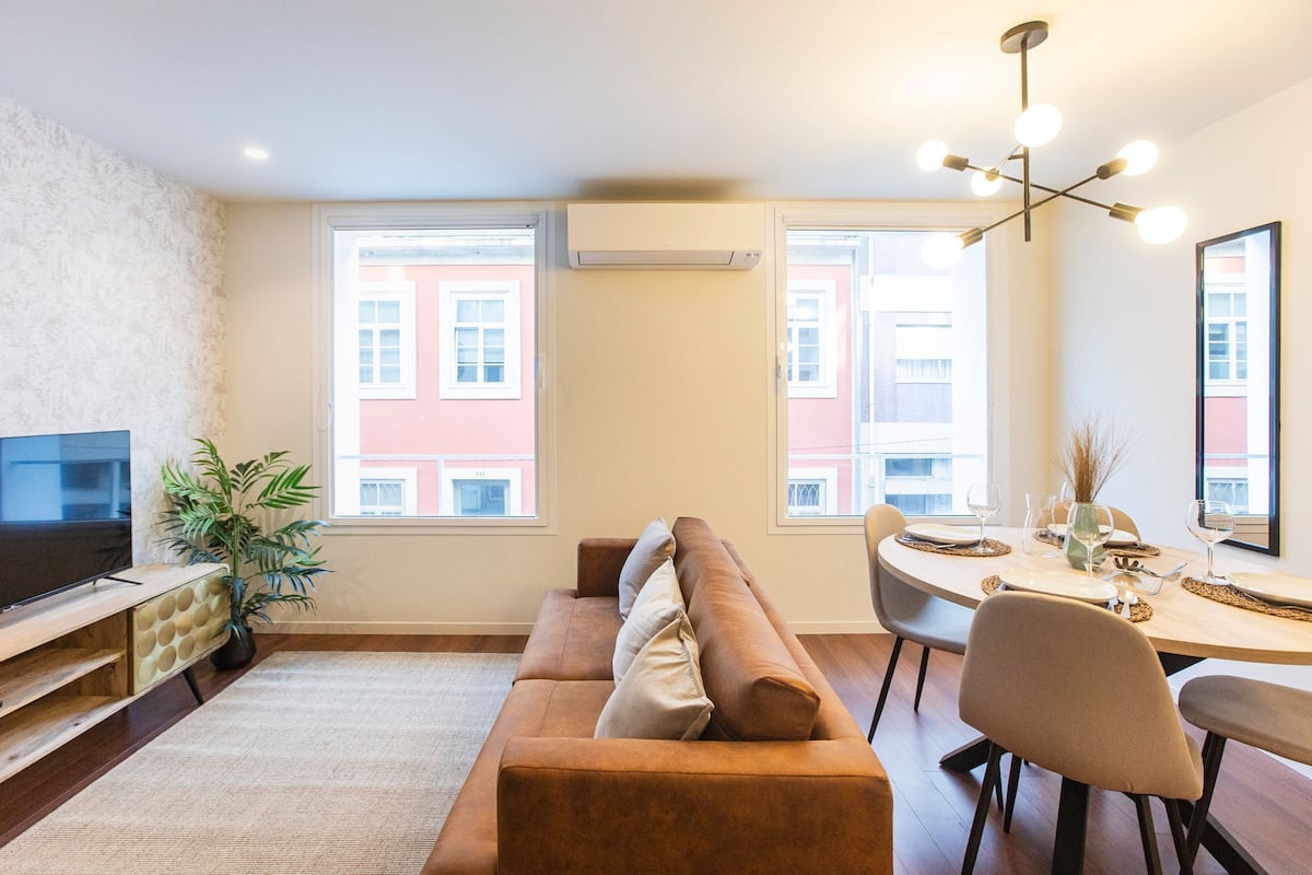 A modern living room with a sofa, TV, dining table, and chairs.