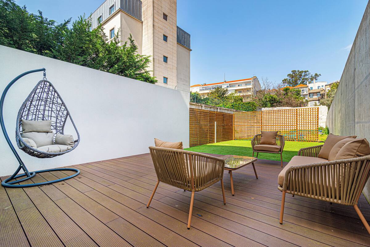 A wooden deck with wicker furniture and a hanging chair.