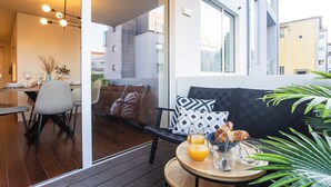 Un área de estar moderna con una mesa de comedor, sillas, un sofá con cojines estampados y una mesa redonda con cosas para el desayuno.