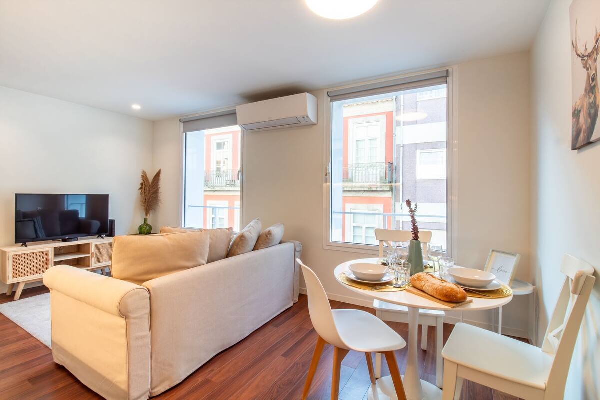 A modern living room with a sofa, TV, dining table, and chairs.