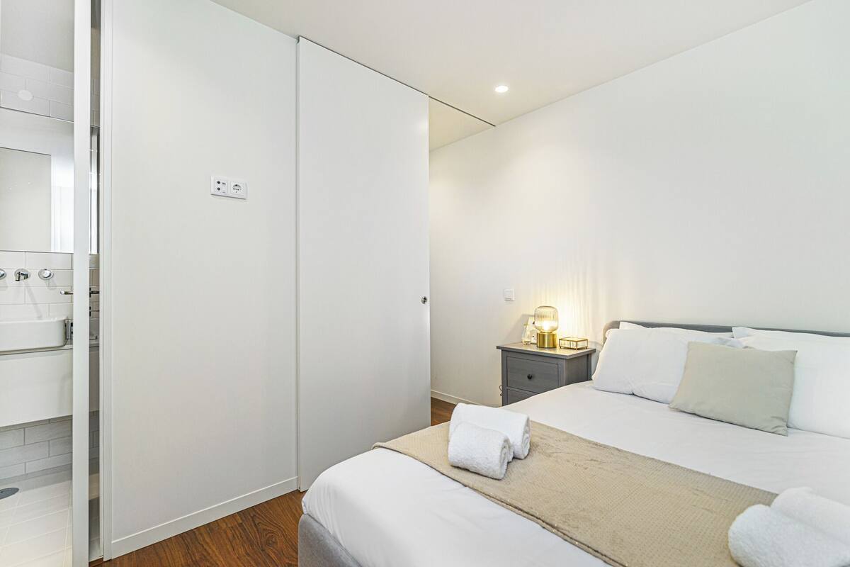 A bedroom with a bed, bedside table, lamp, and a wardrobe.