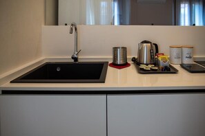 Eine moderne Küche mit einem schwarzen Spülbecken, einem Edelstahlkocher und zwei weißen Behältern mit Deckeln.