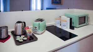 Uma cozinha compacta com cafeteira, torradeira, micro-ondas e uma bandeja com forminhas para cupcakes.