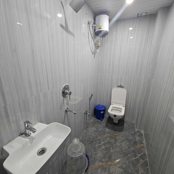 A bathroom with a sink, toilet, shower, and a water heater. - The Shivaay Palace (Varanasi)