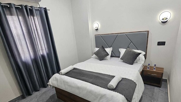 Une chambre moderne avec un lit, des rideaux, une table de chevet et un climatiseur fixé au mur.