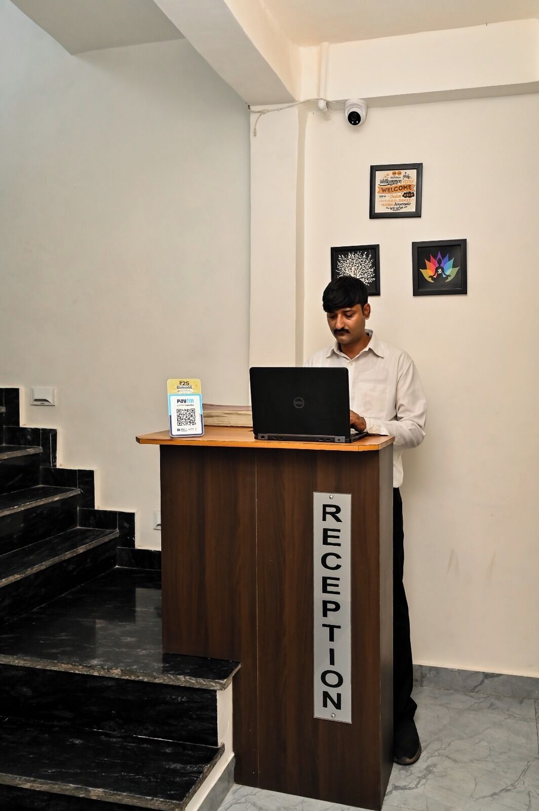 A reception desk with a laptop, a QR code, and a sign indicating 'RECEPTION'.