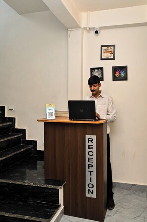 A reception desk with a laptop, a QR code, and a sign indicating 'RECEPTION'. - The Shivaay Palace (Varanasi)