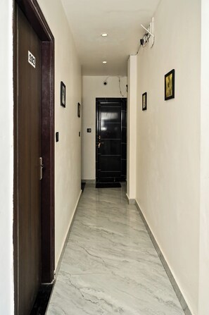 A hallway with a marble floor, a black door with a number sign, and a framed picture on the wall. - The Shivaay Palace (Varanasi)