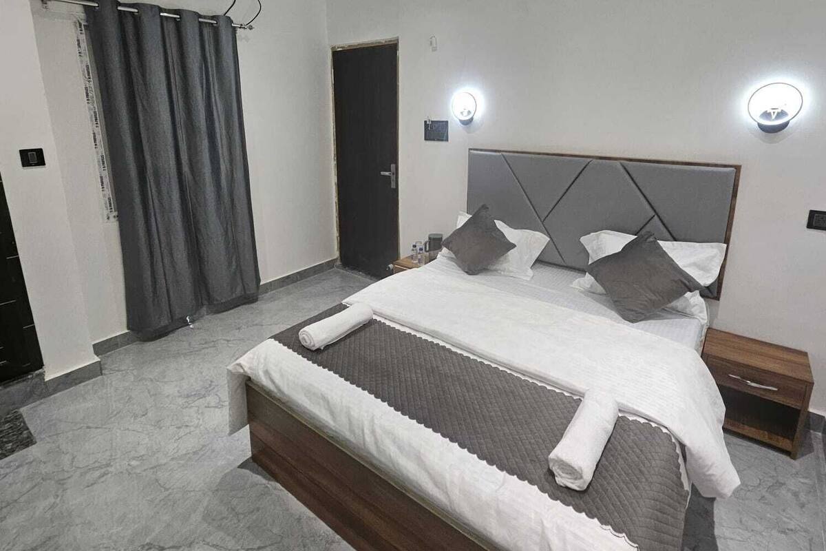 Un dormitorio moderno con una cama grande, una puerta oscura y un aire acondicionado instalado en la pared.