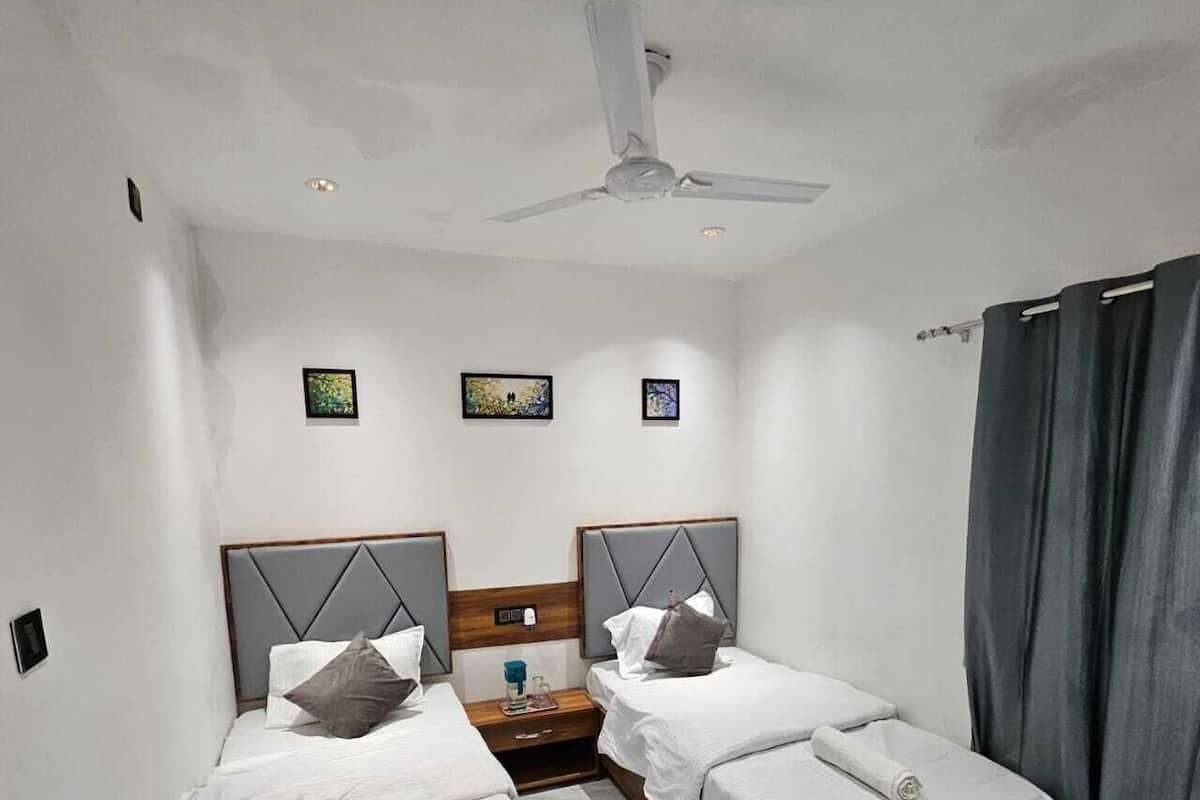 Una habitación de hotel con dos camas individuales, un ventilador de techo y obras de arte en las paredes.