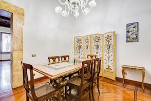 A dining area with a marble table, wooden chairs, a chandelier, and a decorative screen. - Historical Apartment near Piazza Navona (Rome)