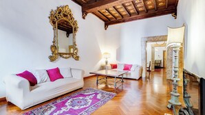 A spacious living room with a white sofa, a patterned rug, a wooden coffee table, and a decorative lamp. - Historical Apartment near Piazza Navona (Rome)
