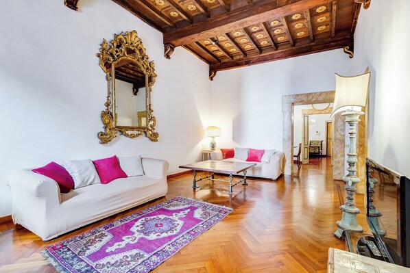 A spacious living room with a white sofa, a patterned rug, a wooden coffee table, and a decorative lamp. - Historical Apartment near Piazza Navona (Rome)