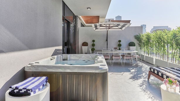 Une terrasse extérieure moderne dotée d’un jacuzzi, d’un espace salon et de plantes en pot.