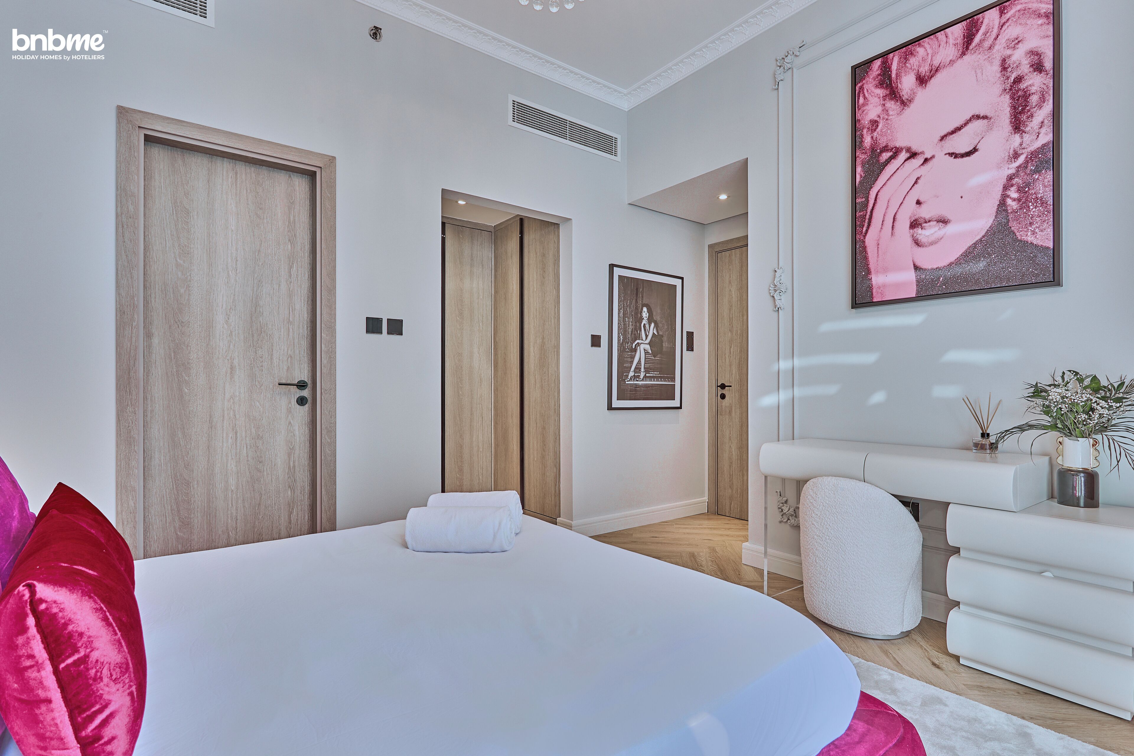 A modern hotel room with a large bed, wooden doors, a white console table, and a framed picture on the wall.