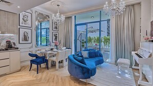 Un salon moderne avec un canapé bleu, un coin repas doté d’une table blanche et un piano.