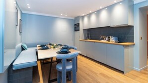 A compact kitchen with a dining area, featuring a light blue color scheme, wooden flooring, and modern appliances. - Superb AC Apartment Center of Paris (Paris)