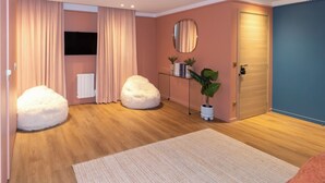 A modern living room with a wooden floor, two white poufs, a large rug, a potted plant, a mirror, and a door. - Superb AC Apartment Center of Paris (Paris)