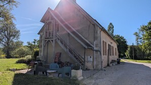 A building with a staircase, outdoor seating, and a gravel driveway. - Cottage in forest with garden, terrace and parking near Loire (Saint-Firmin-sur-Loire)