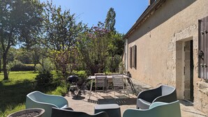 A patio with outdoor furniture, a grill, and a view of a garden with trees and flowers. - Modular cottages between Loire and Sologne with garden and BBQ (Saint-Firmin-sur-Loire)