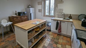 Una cocina compacta con una mesa de madera, un refrigerador blanco, un microondas y una ventana con vistas.