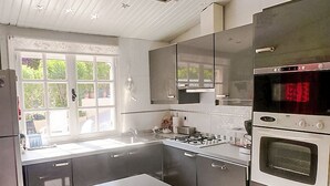 Una cocina moderna con electrodomésticos de acero inoxidable, un ventanal y vistas al exterior.