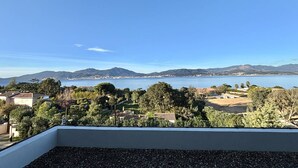 En balkon med udsigt over et sølandskab, bjerge og frodig vegetation.