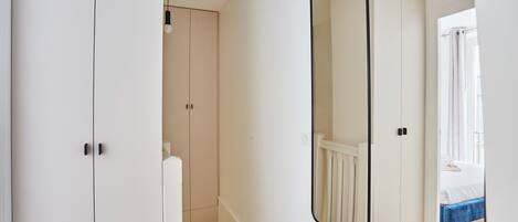 A bedroom with a bed, a mirror, and a wardrobe.
