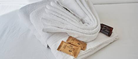 A neatly folded white towel with two small brown packets labeled "WELCOME" on a white surface.