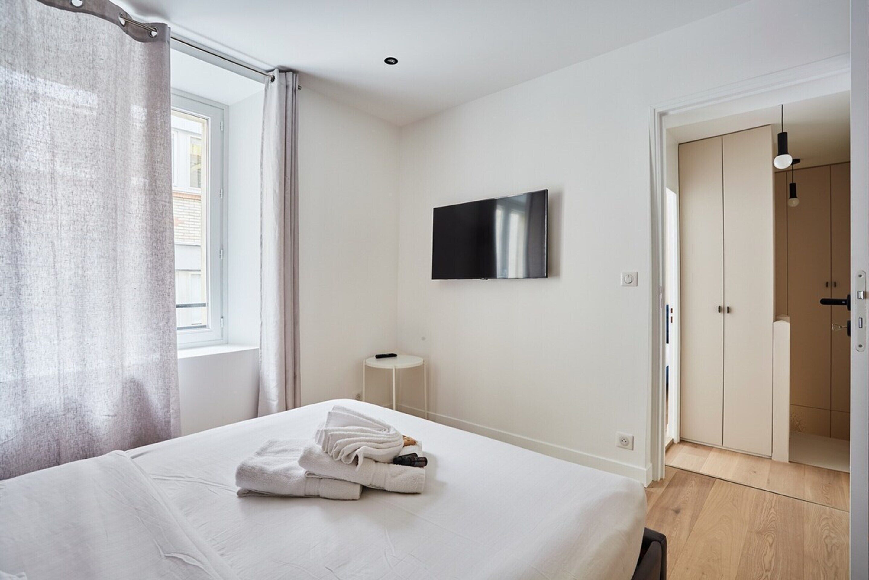 Una camera d'albergo con un letto, una TV a schermo piatto, un comodino e un armadio.