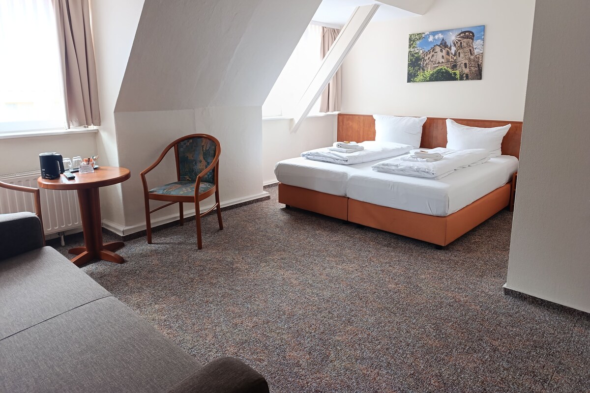 Une chambre d’hôtel avec un lit, un bureau, une chaise et un tableau au mur.