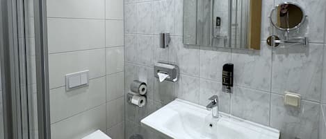 A modern bathroom with a white sink, a toilet, a mirror, and a towel rack.