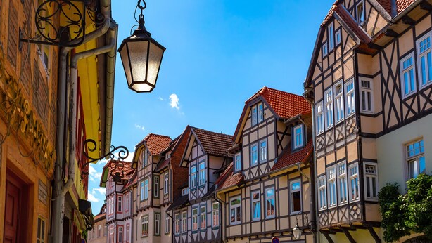 A narrow street lined with traditional half-timbered buildings, a street lamp, and a clear blue sky. - Regiohotel Bunte Stadt Wernigerode (Wernigerode)