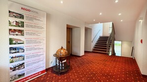 A hotel lobby with a red carpet, a globe, and a staircase. - Regiohotel Bunte Stadt Wernigerode (Wernigerode)