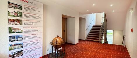 A hotel lobby with a red carpet, a globe, and a staircase.