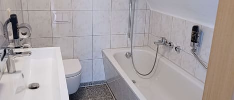 A modern bathroom with a white sink, toilet, and bathtub.