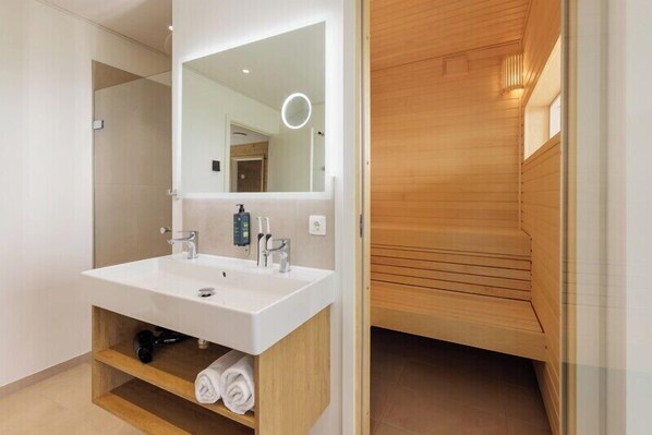 A modern bathroom with a large mirror, white sink, and wooden vanity.