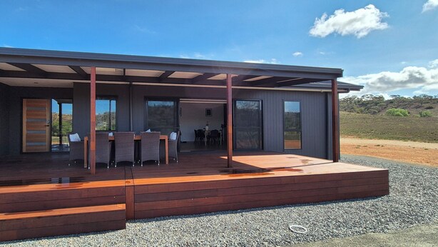 A modern house with a covered patio area, large windows, and a gravel driveway. - The Black House at Mannum (Mannum)