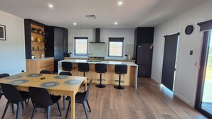 A modern kitchen with a dining area, featuring a wooden table, black chairs, and a black refrigerator. - The Black House at Mannum (Mannum)