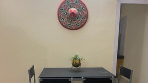 Ein Essbereich mit Tisch und vier Stühlen, einem Wandbehang und einem Blumentopf.