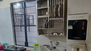 Eine Küche mit Gaskochfeld, Edelstahlspüle, Geschirrgestell und Wasserspender.