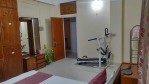 Ein Schlafzimmer mit Bett, Schrank, Spiegel, Tür und Fitnessgerät.