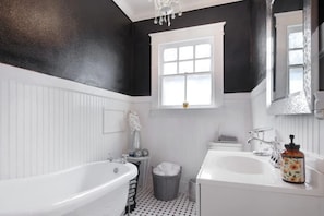 A bathroom with a bathtub, a sink, and a window.